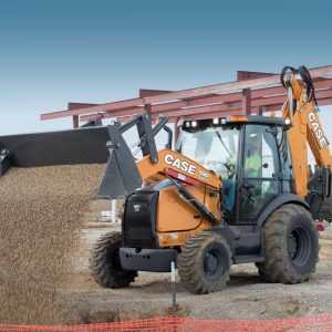 Backhoe loader digger in action pouring gravel over a pipe trench
