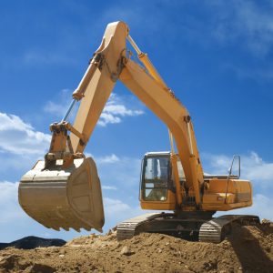 An excavator digger on top of a small hill of earth, working at moving earth