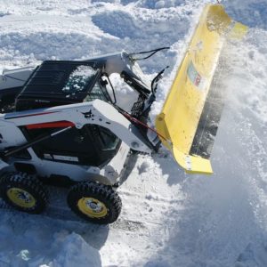 A skid steer at work clearing snow